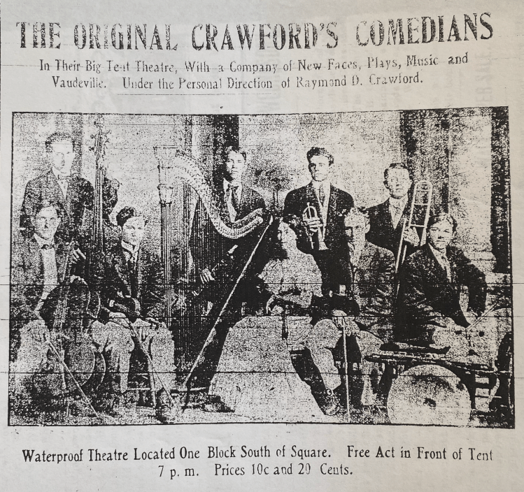 Old faded newspaper clipping with the headline "The Original Crawford's Comedians: In Their Big Tent Theater With a Company of New Faces, Plays, Music, and Vaudeville. Under Personal Direction of Raymond D. Crawford." The image depicts nine musicians posed with instruments. Eight are white men and one is a white woman in a white dress seated with a large harp.The men are wearing suits and are either sitting or standing next to their instruments which include: cello, stand up double bass, clarinet, coronet, violin, trombone, and drums. Below the image, are the words: "Waterproof Theater Located One Block South of Square. Free Act in Front of Tent 7 p.m. Prices 10c and 20 Cents."